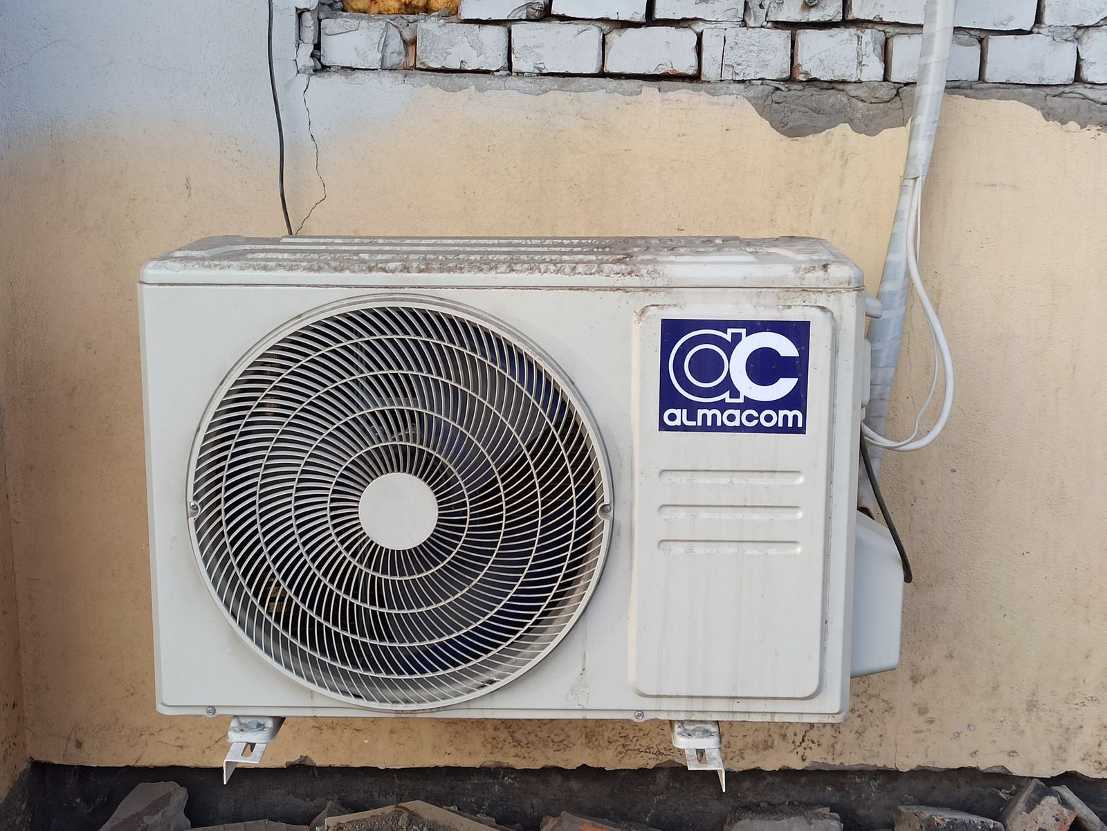Uma unidade de ar condicionado externa bem utilizada fixada a uma parede de tijolos, exibindo controle climático urbano.